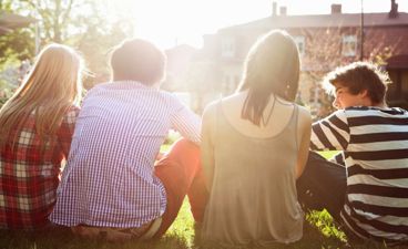 Gjeng med ungdom sitter i solen.