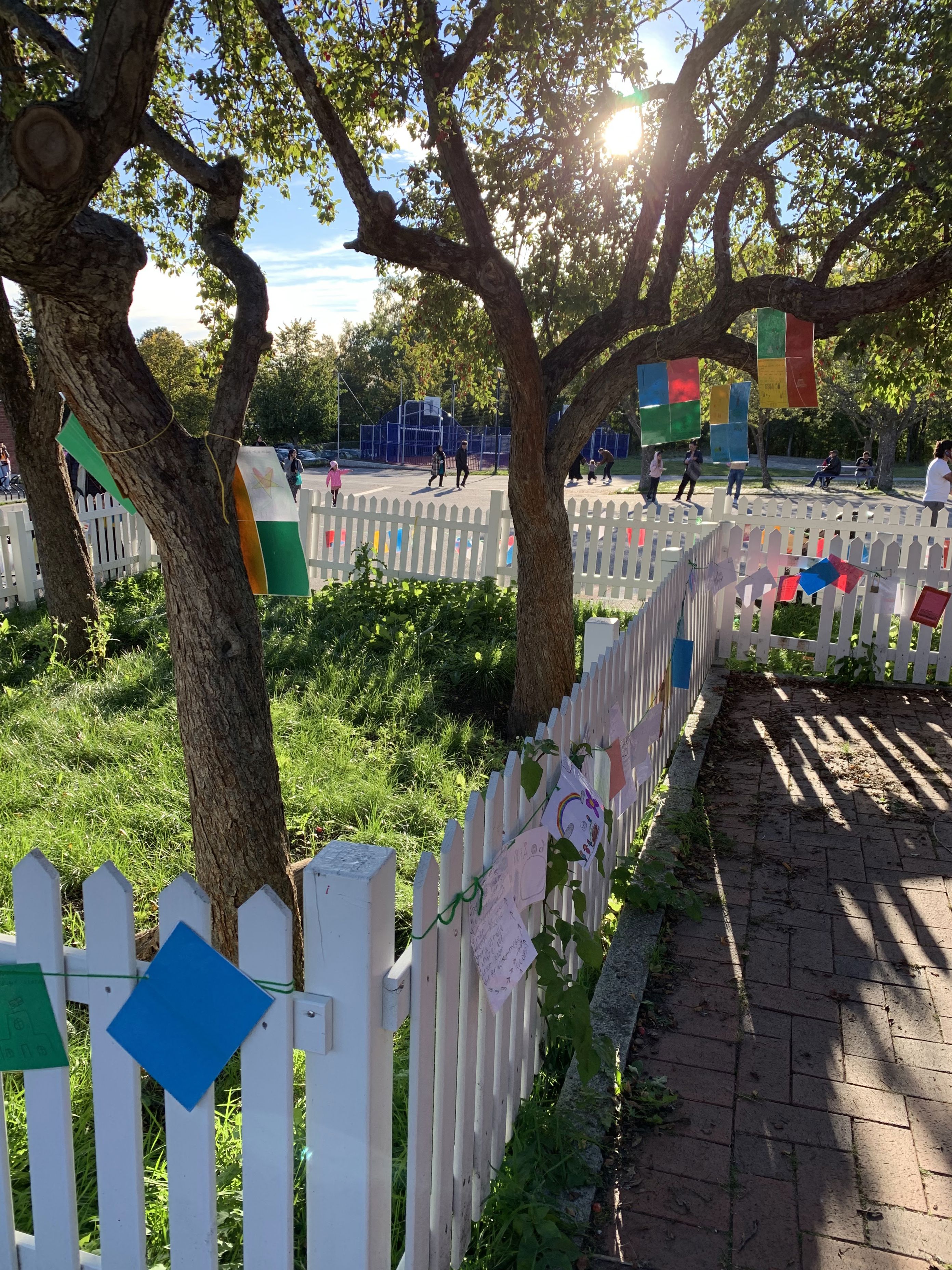 et hvitt gjerde med et tre og et hvitt stakittgjerde med et hvitt stakittgjerde og en gate