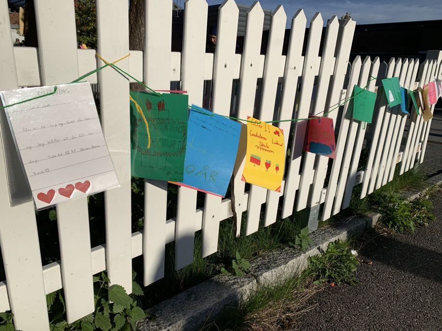 et hvitt stakittgjerde med fargerike skilt