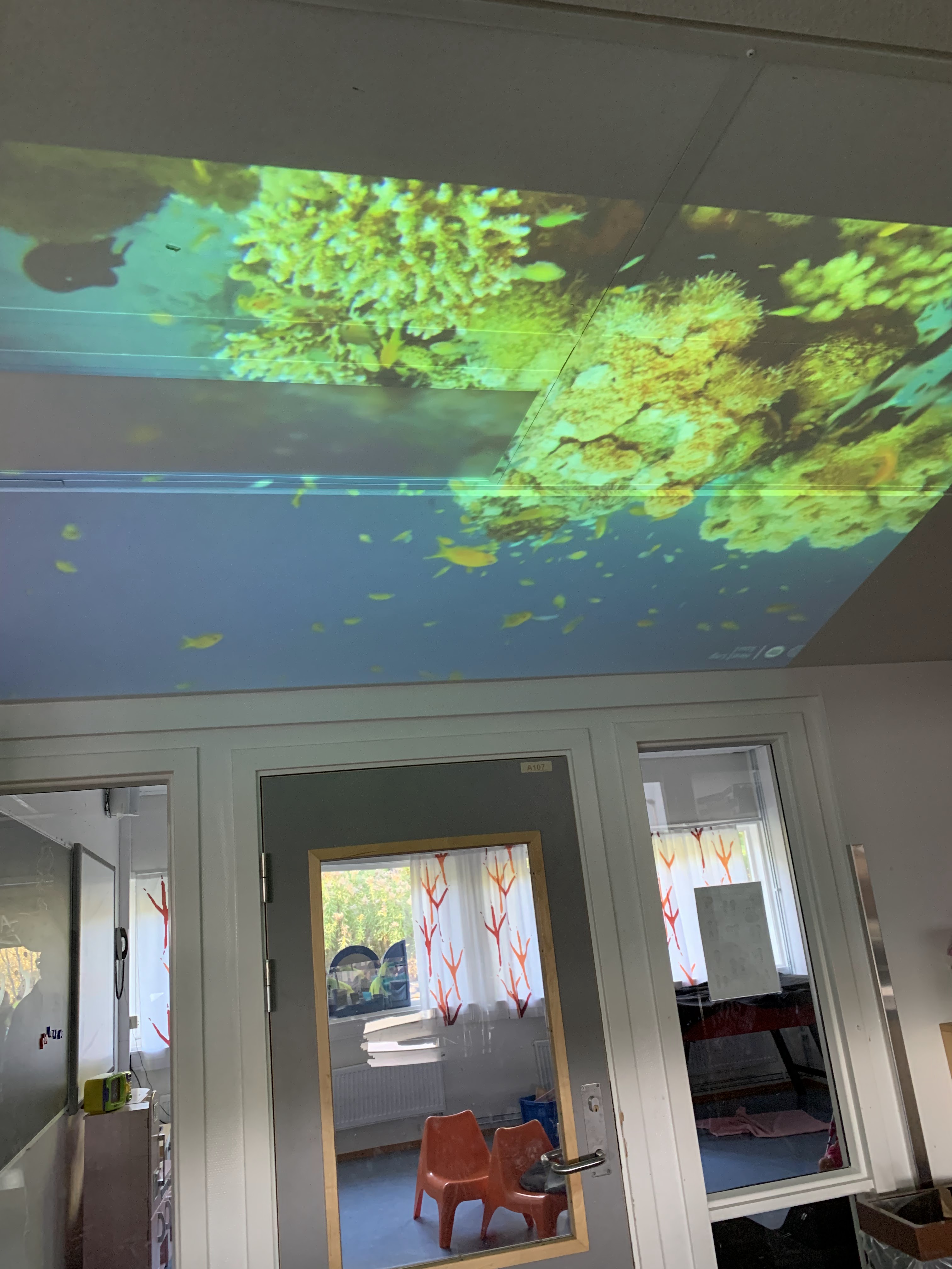 et rom med grønt tak og en dør med vindu og grønt lys