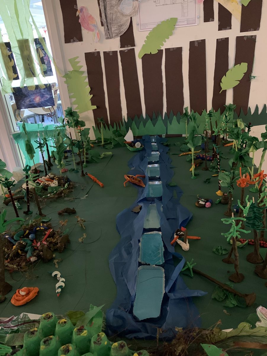 en statue av en person omgitt av planter og en vegg med et vindu