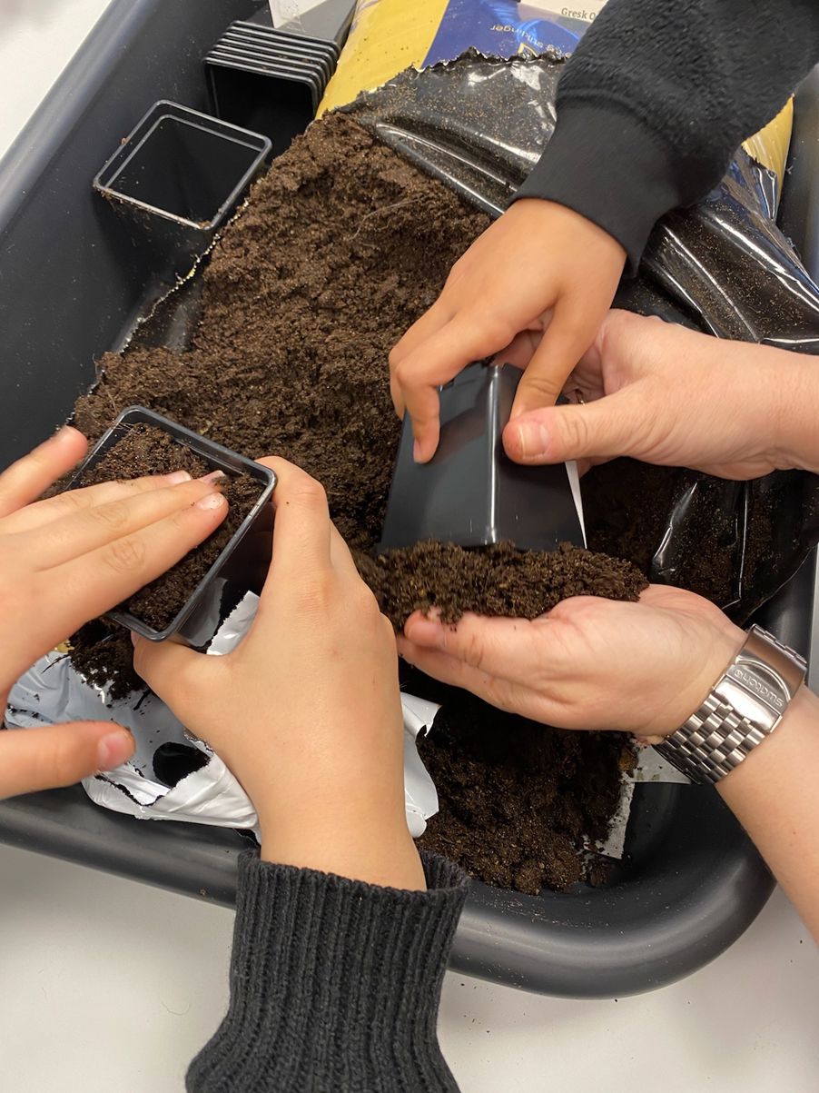 hender som holder en svart beholder med smuss